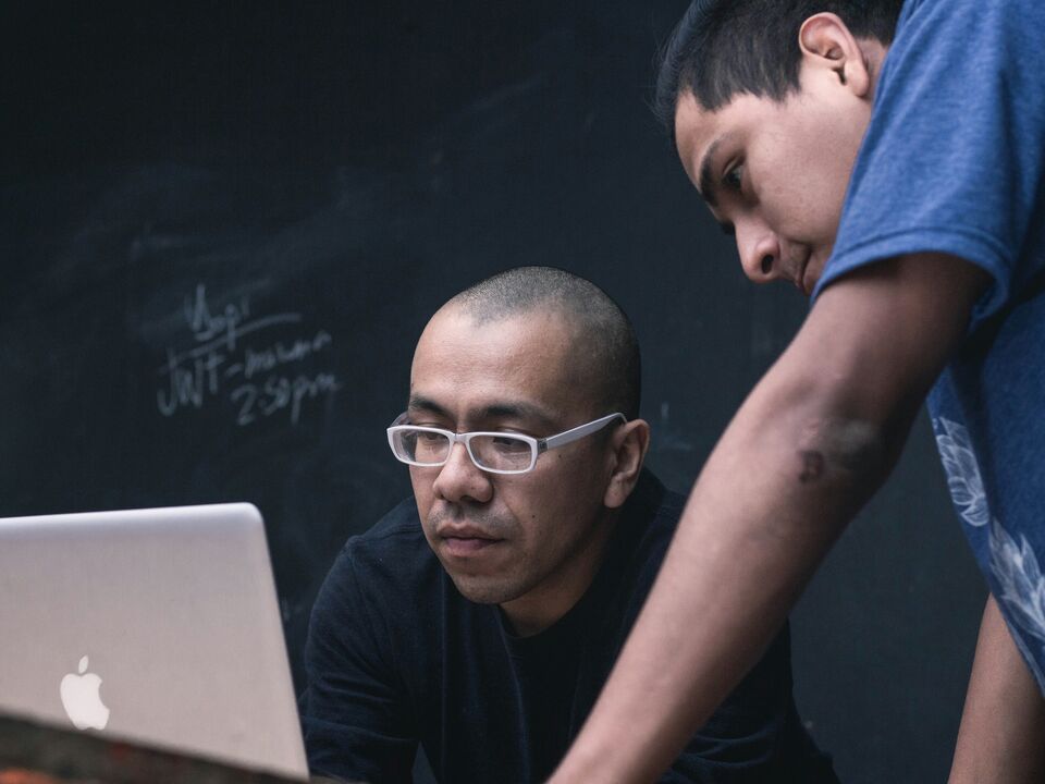 A domain expert and a colleague reviewing technical work together on a laptop