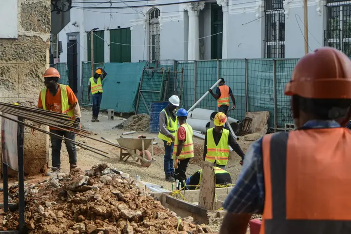 A crew in hard hats and hi-vis working along an excavated street.