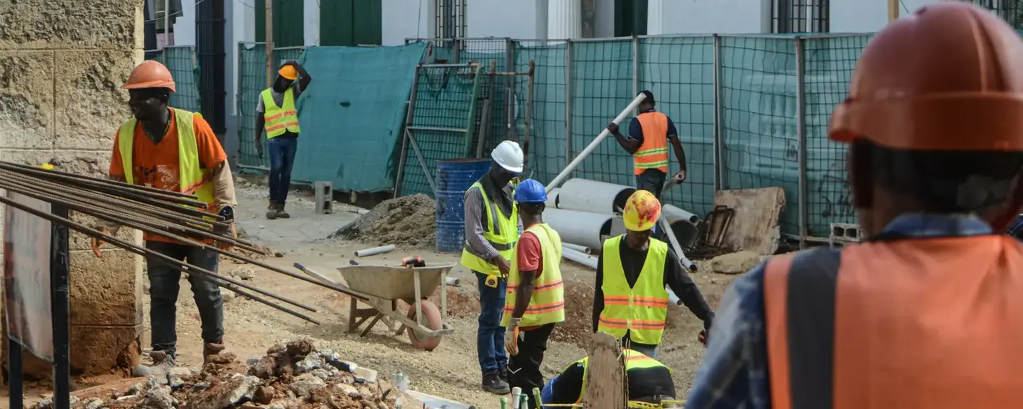 A crew in hard hats and hi-vis working along an excavated street.